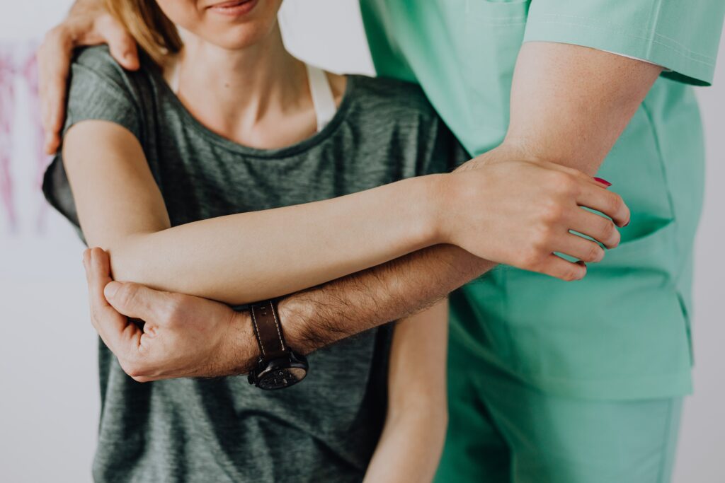 Physiotherapist providing hands-on shoulder treatment during a home visit